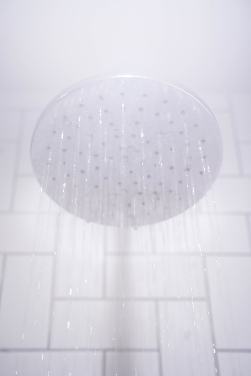 water from round gray stainless steel shower head